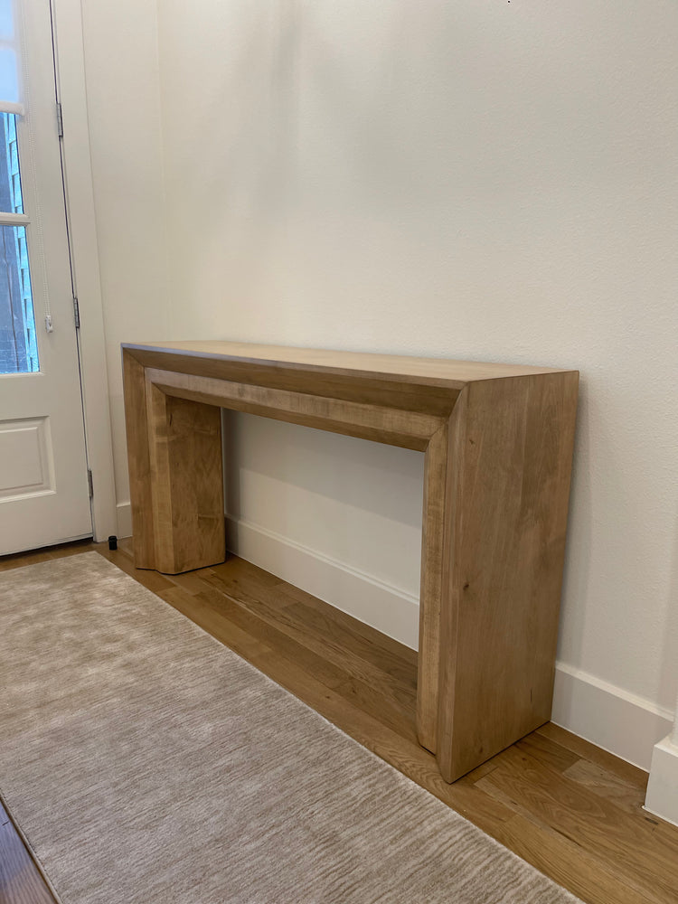 Large thick beige-blonde entry table placed by the entry door, featuring a light, natural finish that adds warmth and style to the space.