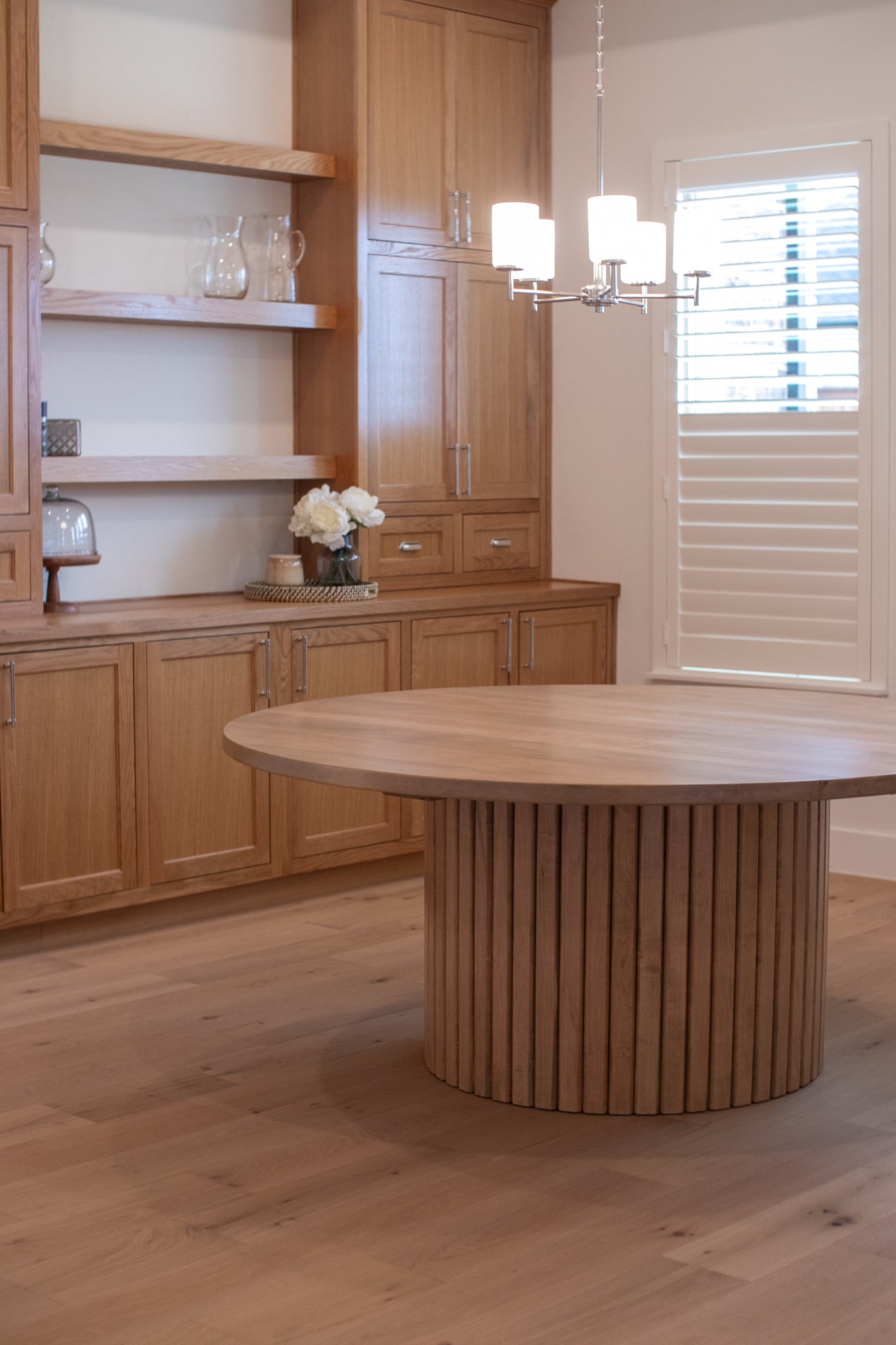 A large fluted base of a dining table in a beautifully designed wooden dining room, showcasing the elegant craftsmanship in a warm, inviting space