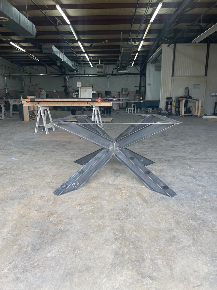 ished metal spider base in a woodworking shop, displaying raw metalwork and the detailed structure, surrounded by tools and wood material