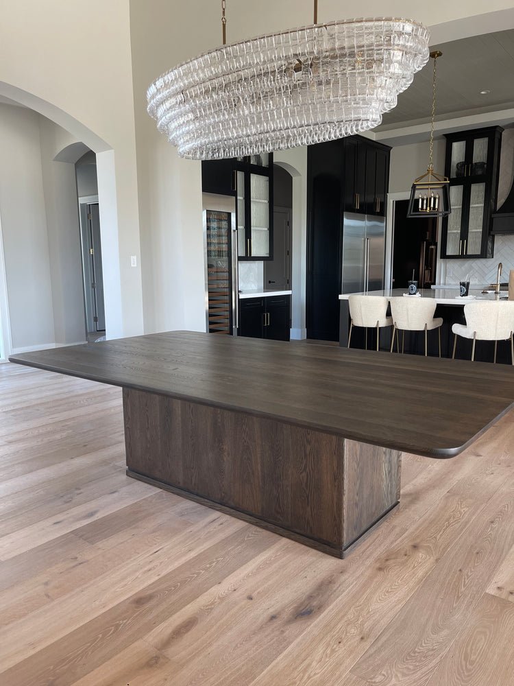 Solid wood Westlake dining table with clean rectangular lines, shown in a dark walnut finish with modern tapered legs, set in a bright dining space