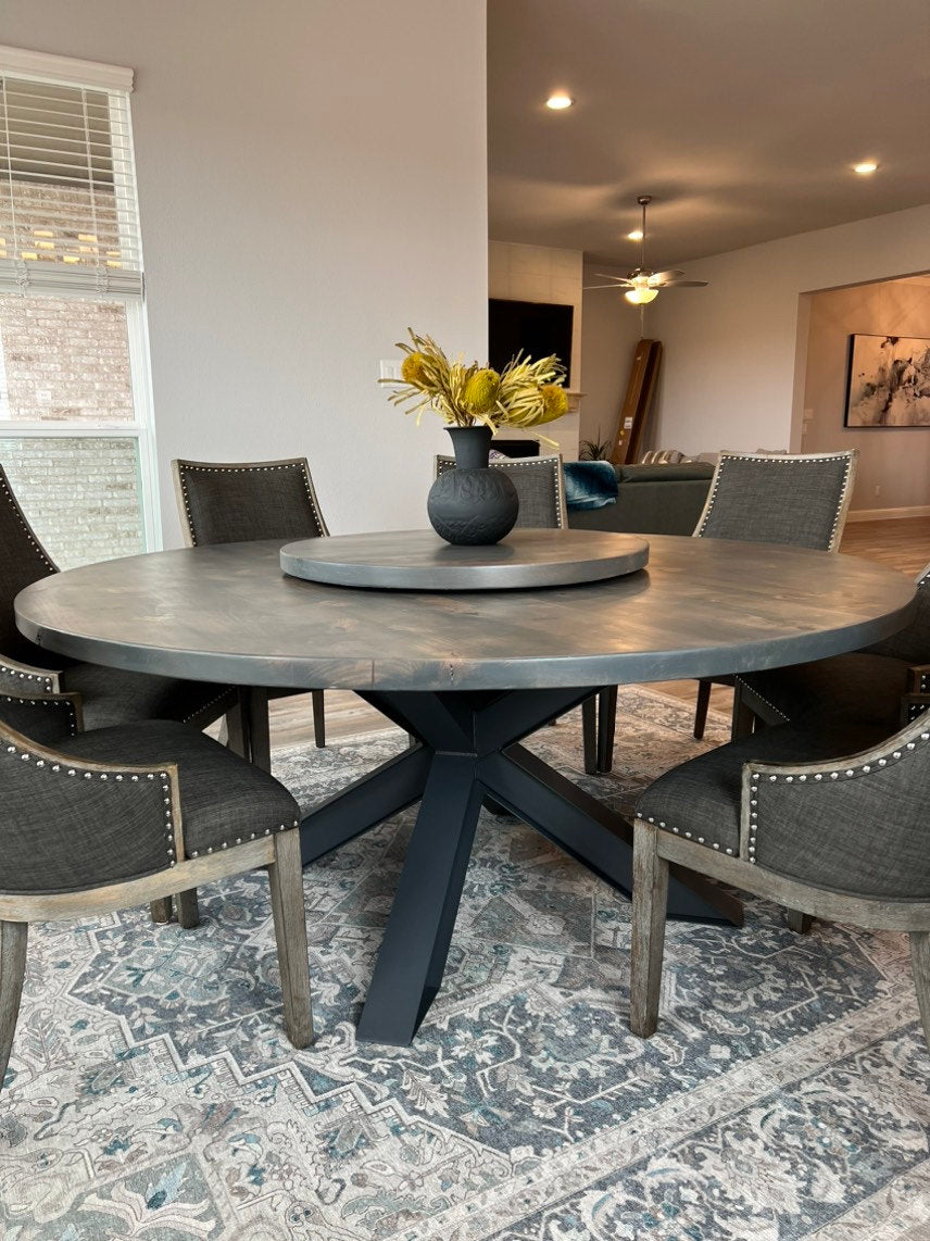 large 72in round dining table surrounded by 7 large brown upholstery chairs with a centerpiece.