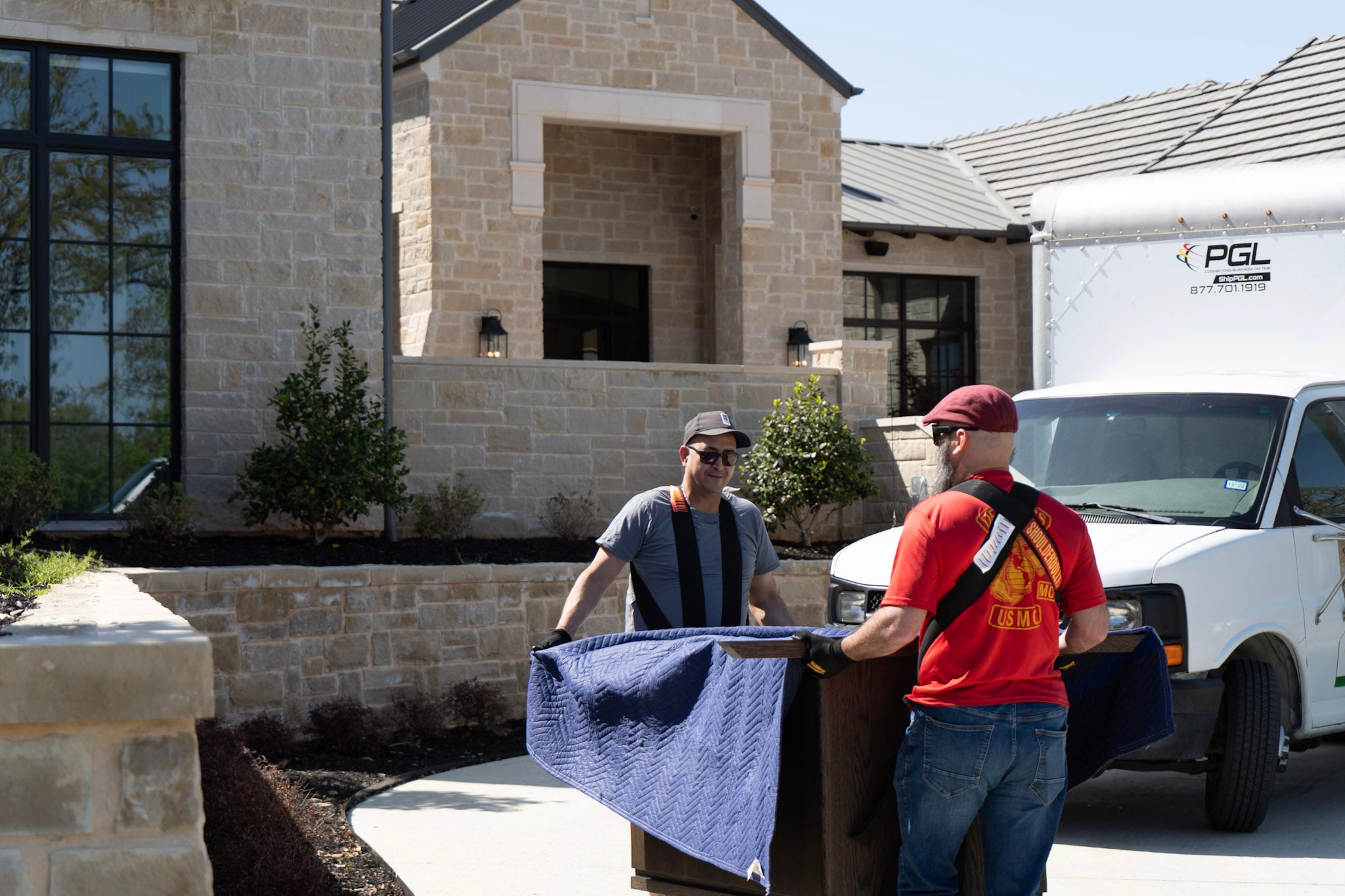 Two men with a toolbox in front of a house, with a white truck labeled 'PGL' in the background.