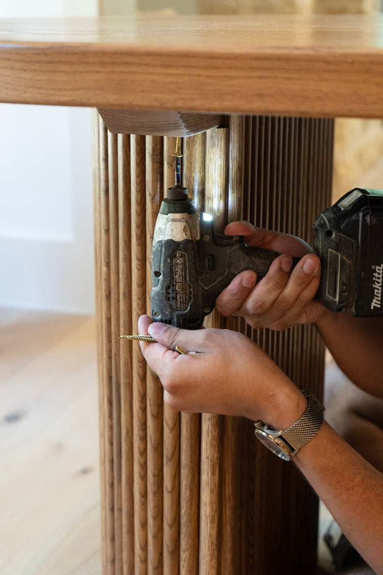 Person using a drill on a wooden table