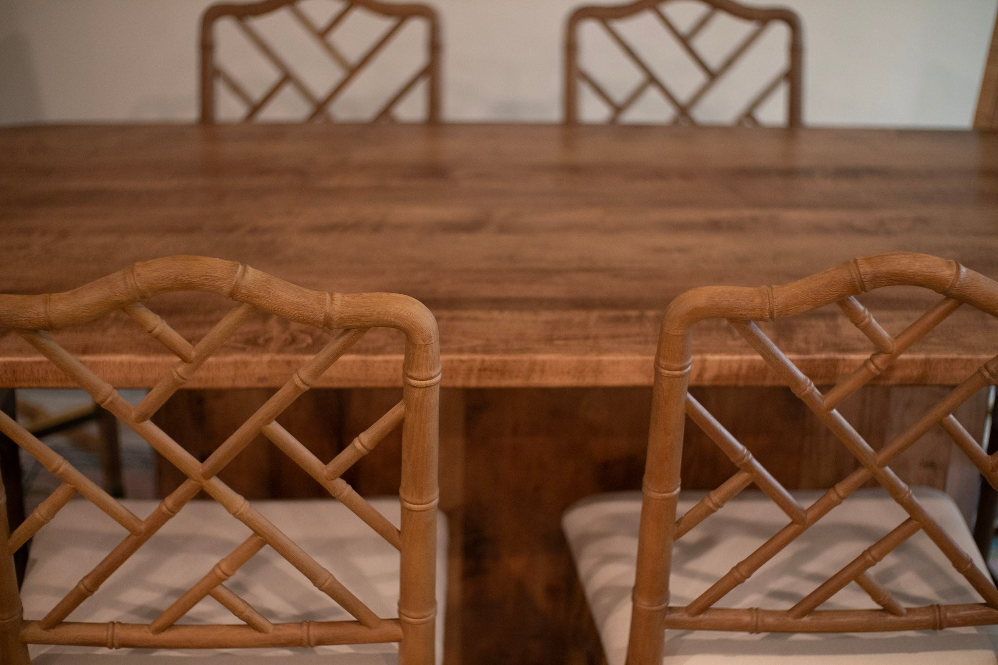 custom maple dining table stained in provincial. it is surrounded by 4 wooden modern/ornate chairs.