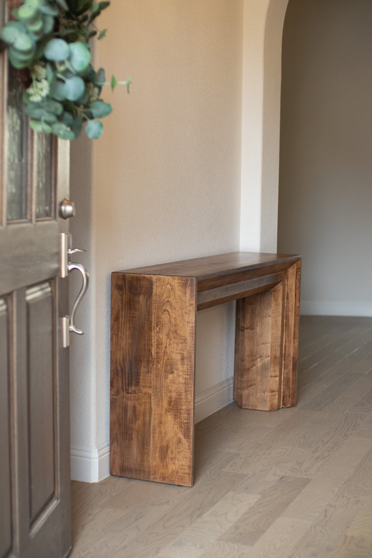 Large dark brown thick entry table positioned near an open door, adding a bold and welcoming presence to the entryway.