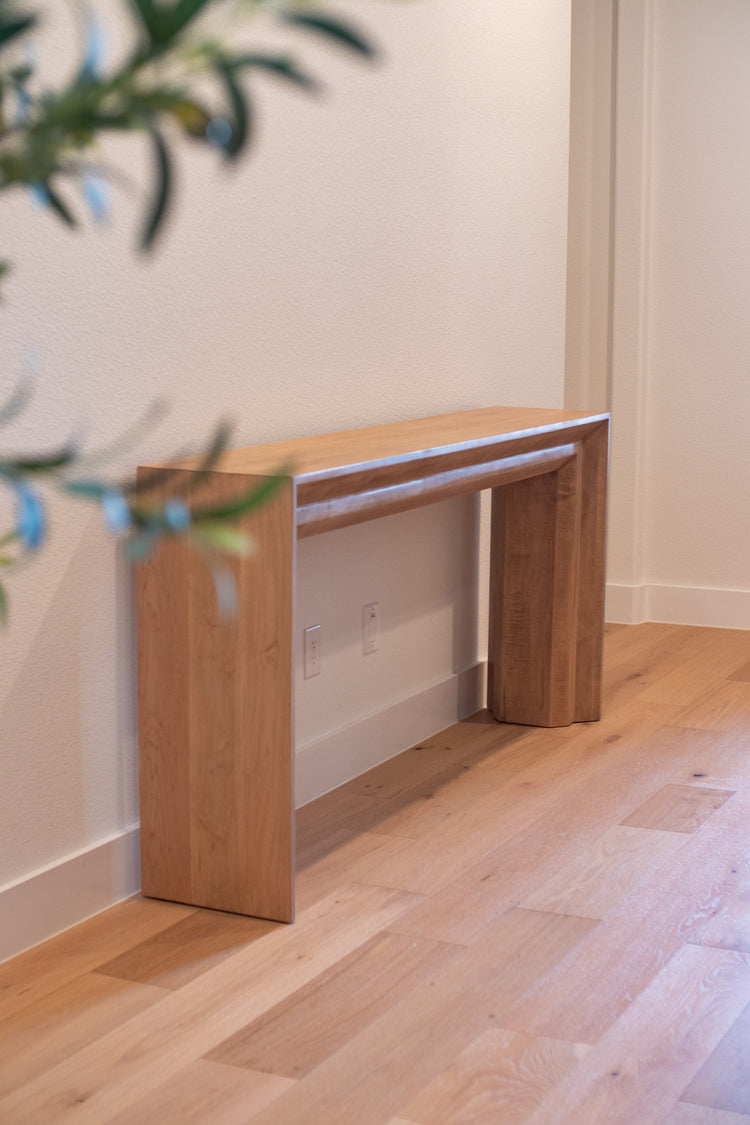 Large thick beige-blonde entry table placed in the entry with a plant, featuring a light, natural finish that adds warmth and style to the space.