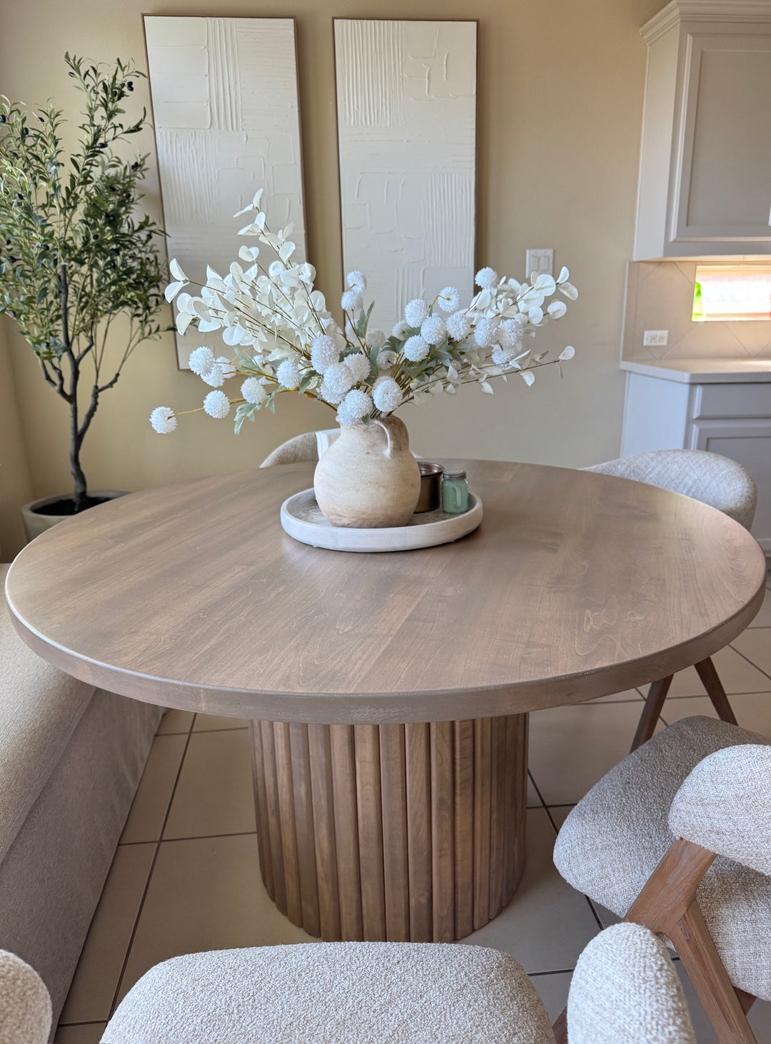 Top view of a light brown fluted round dining table made of maple, surrounded by four modern, comfy chairs, creating a sleek and inviting dining space