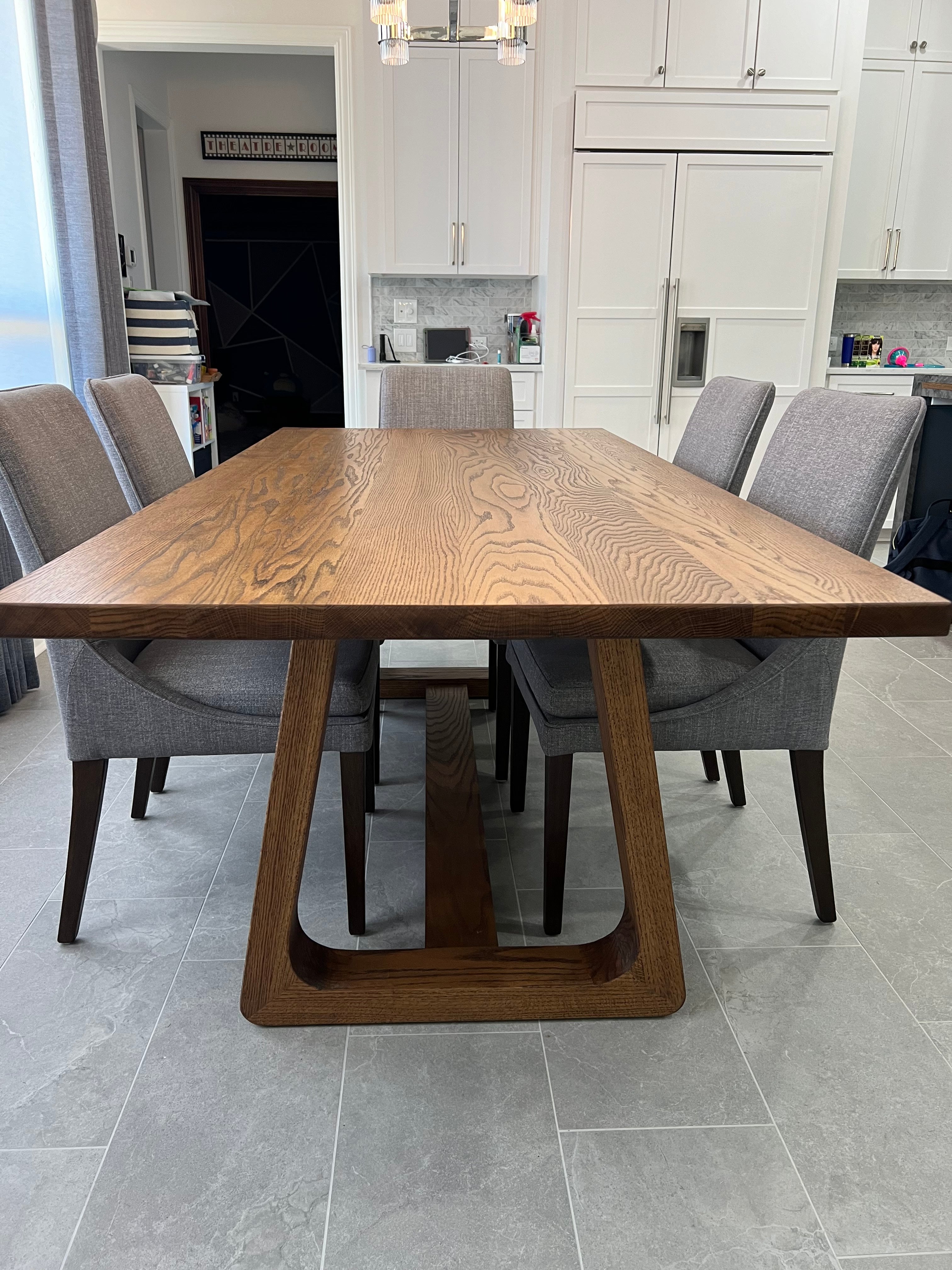 Rectangular oak dining table with a smooth, organic frame, surrounded by five wide upholstered chairs, creating a stylish and comfortable dining space