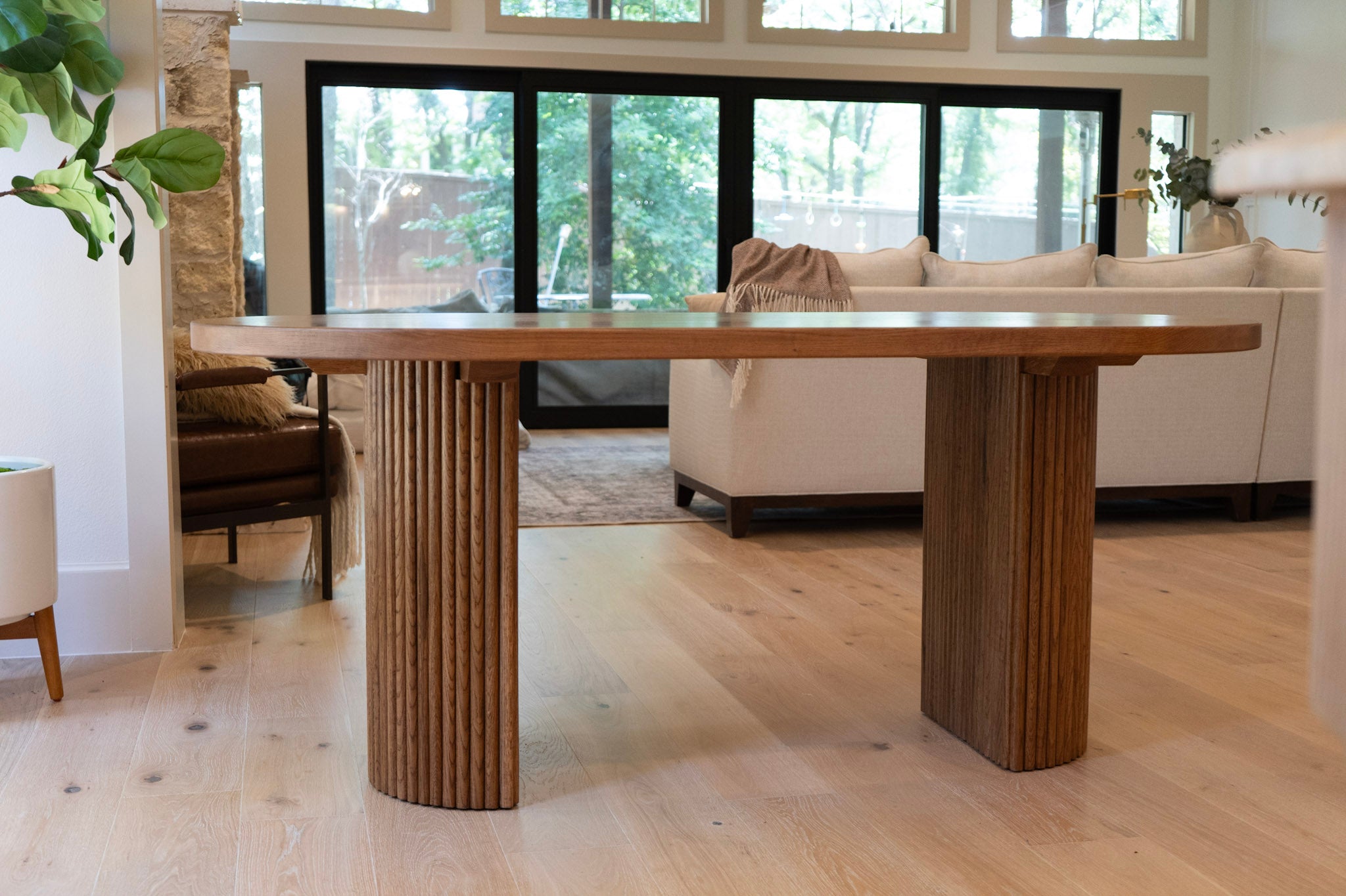 Modern fluted white oak dining table with oval top and half-cylinder base