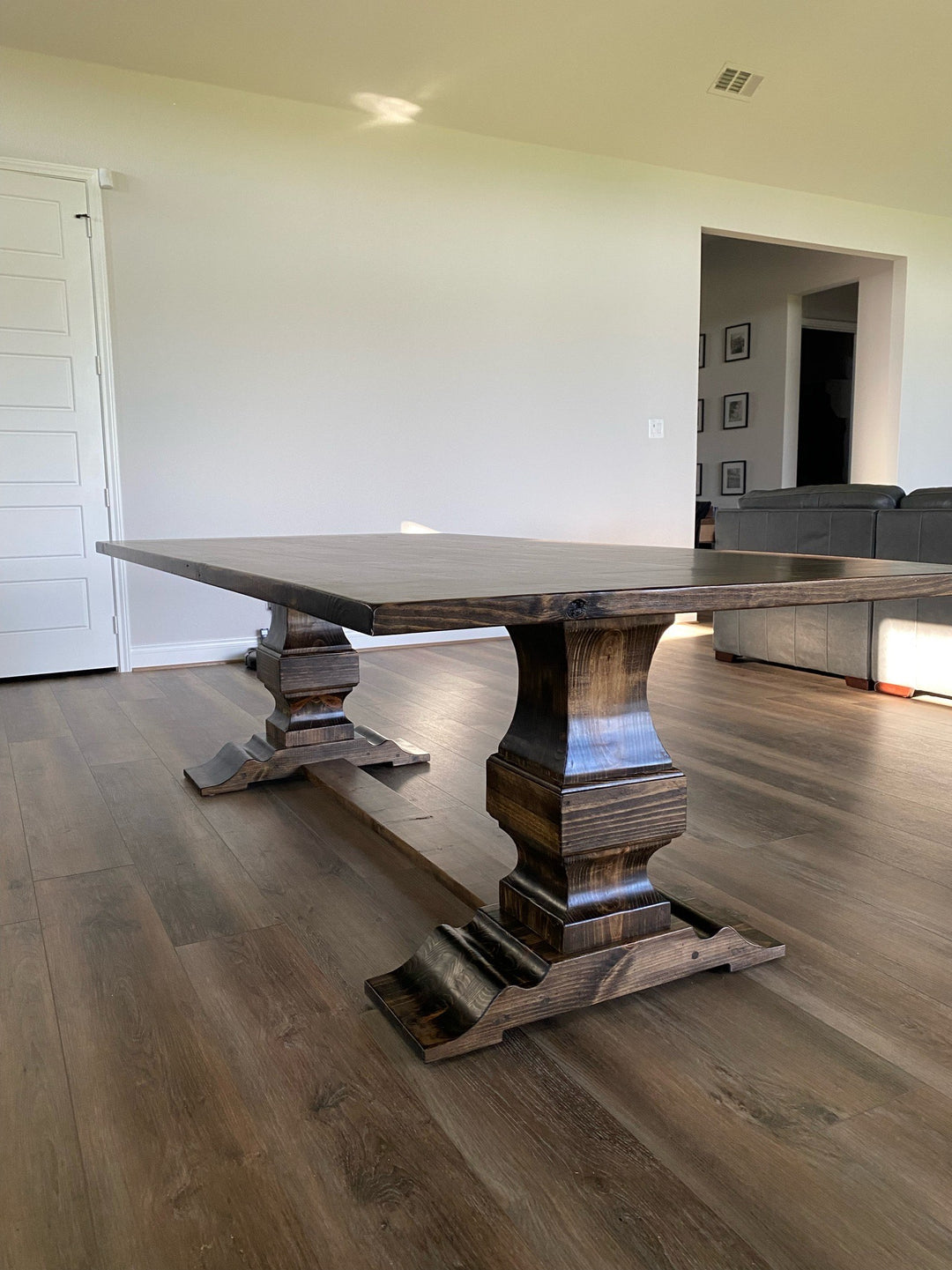 Rectangular wooden handcrafted pedestal dining table showcasing intricate craftsmanship and natural wood details that complement the warm, contemporary design