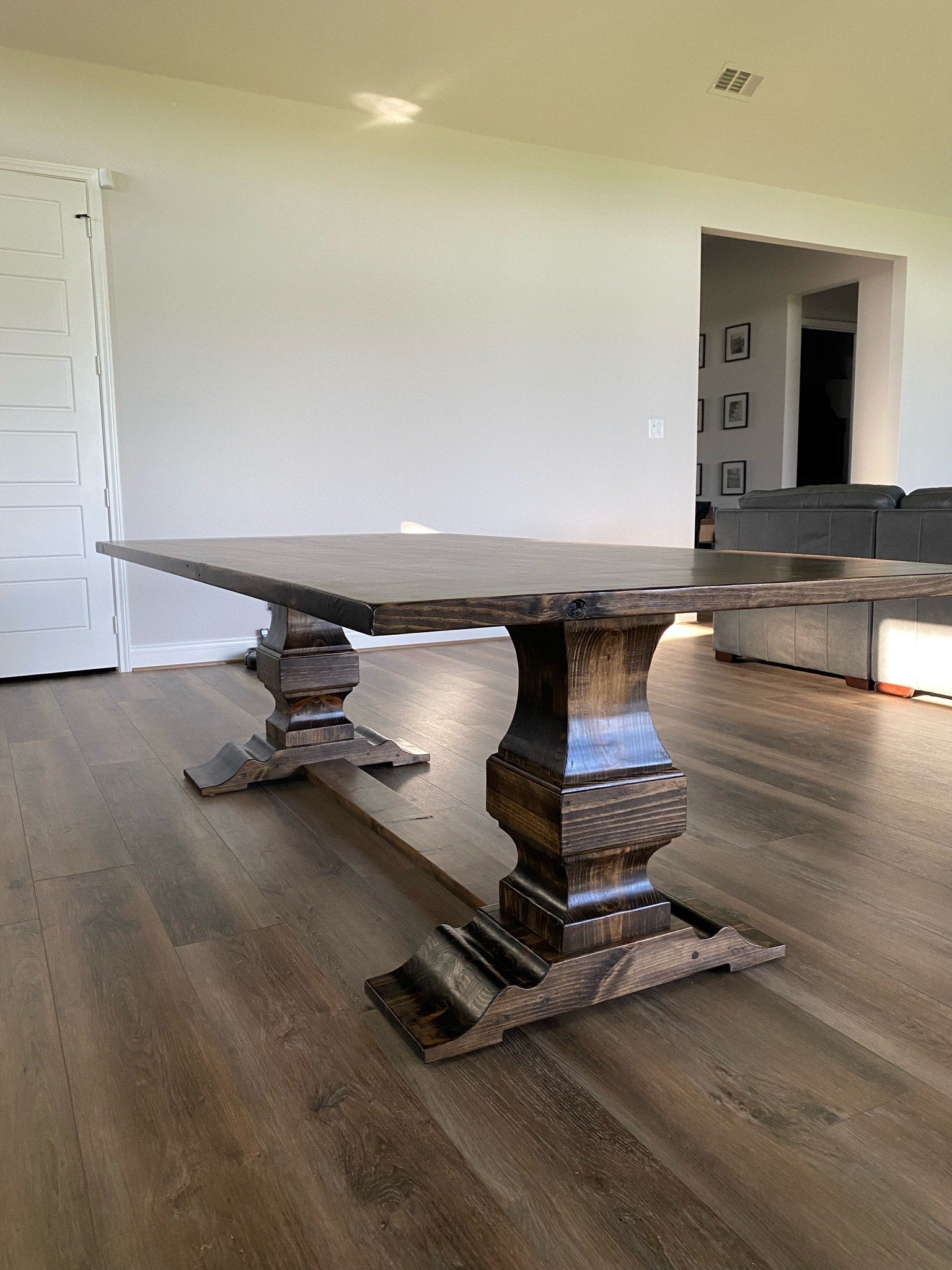 Rectangular wooden handcrafted pedestal dining table showcasing intricate craftsmanship and natural wood details that complement the warm, contemporary design