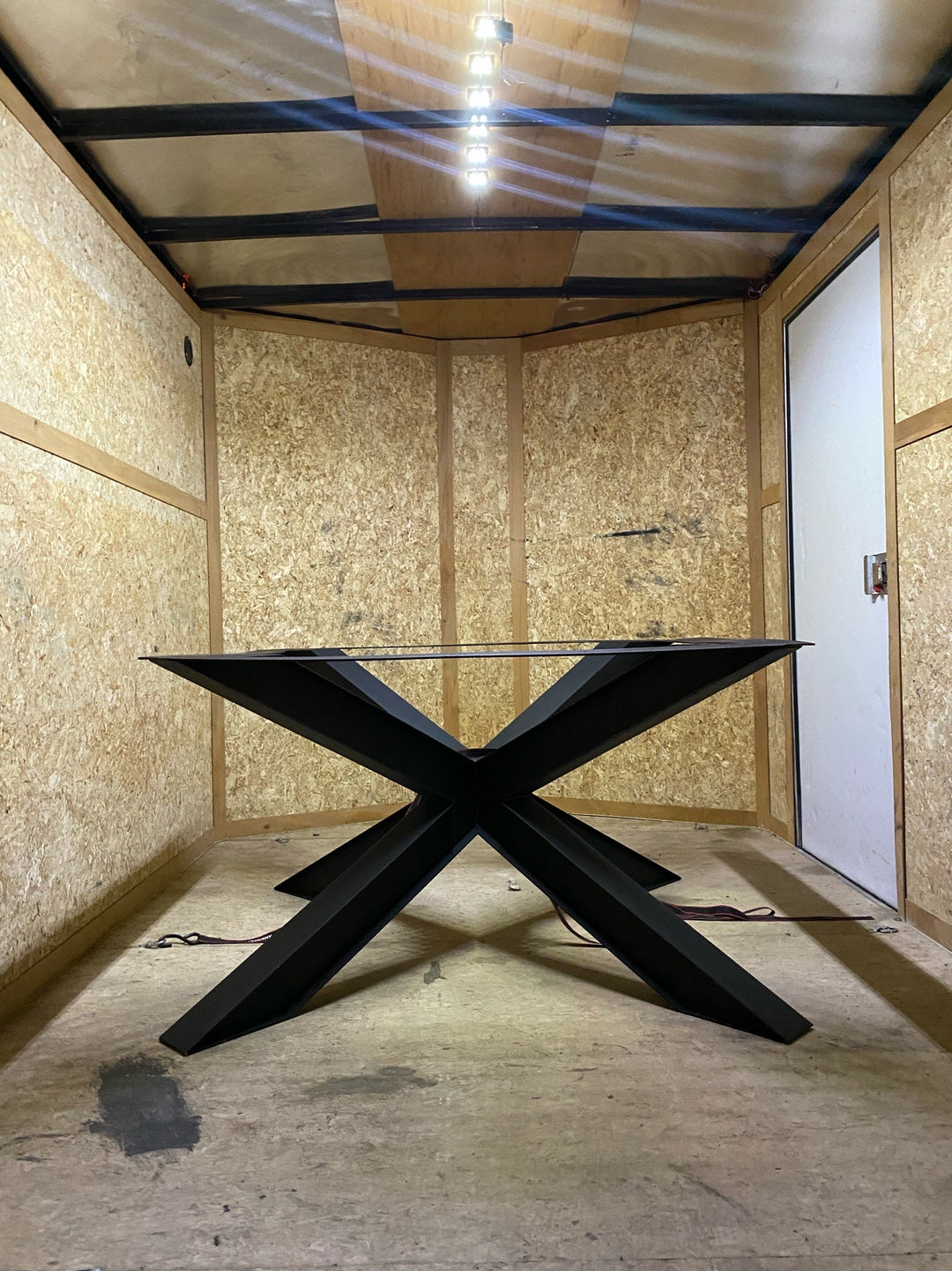 View of a large metal spider base inside a trailer, showcasing the intricate design and sturdy structure against the backdrop of the trailer's interior