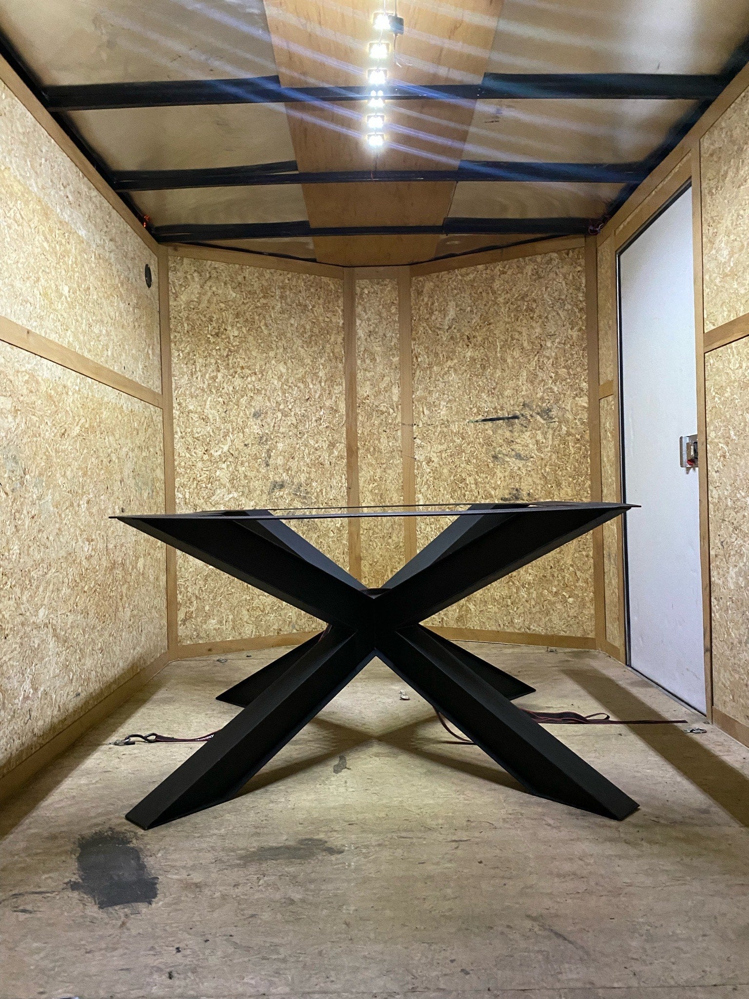 View of a large metal spider base inside a trailer, showcasing the intricate design and sturdy structure against the backdrop of the trailer's interior