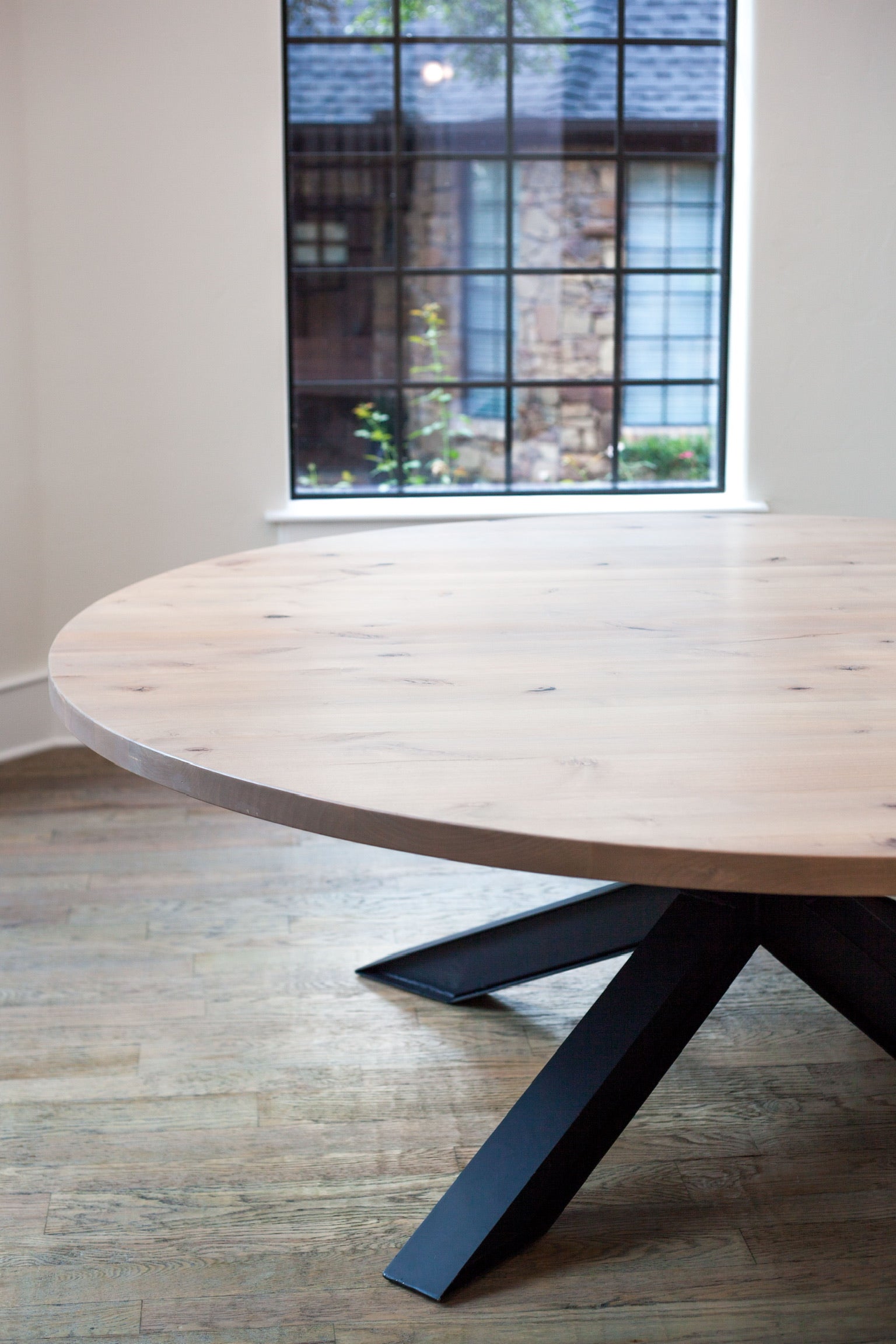 Close-up view of a modern table featuring a black epoxy top and a sharp black metal base, highlighting the sleek and bold design