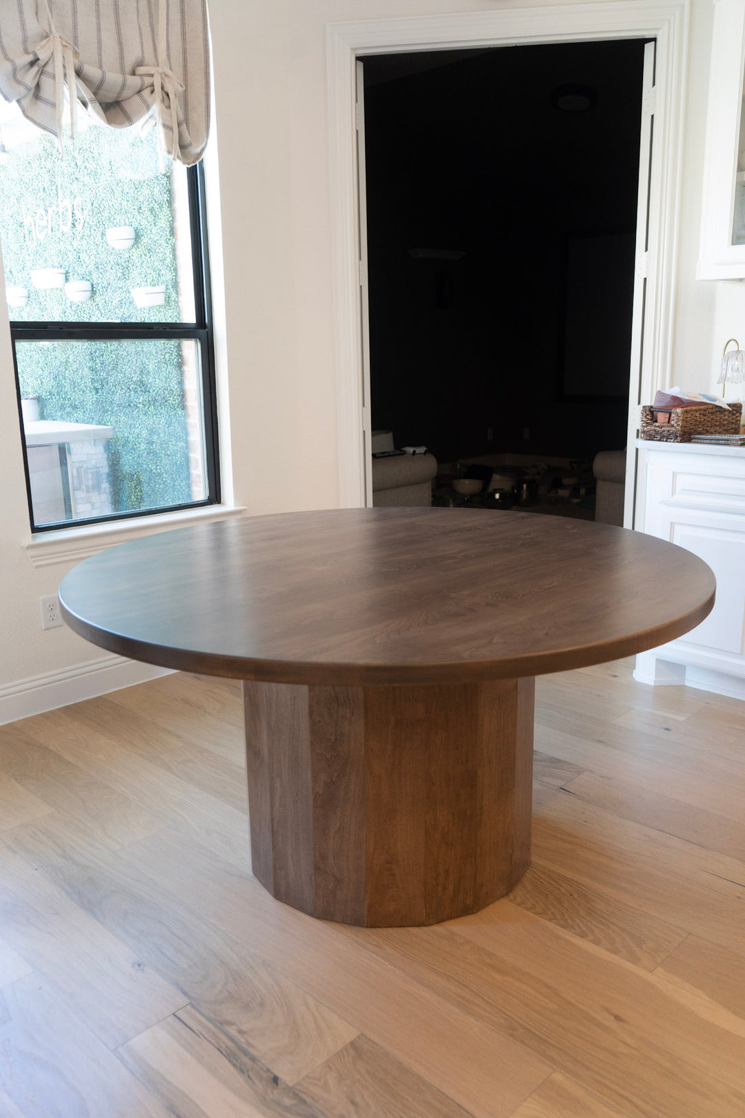 Wooden dining table in a room with large windows and white walls.