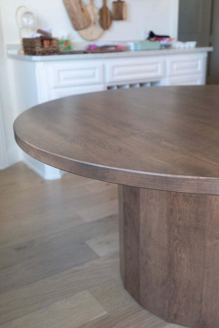 Wooden dining table in a room with a white fireplace and decorative items.