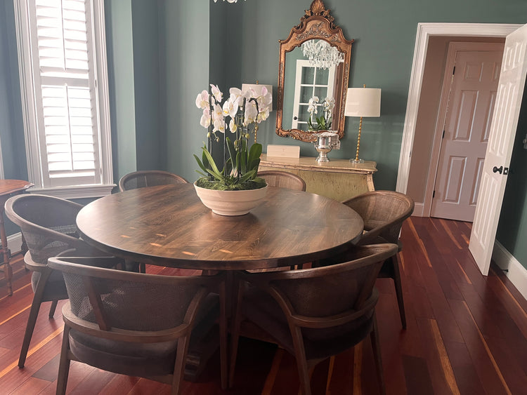 Dining room with a wooden table and chairs, a vase of flowers, and a mirror on the wall.