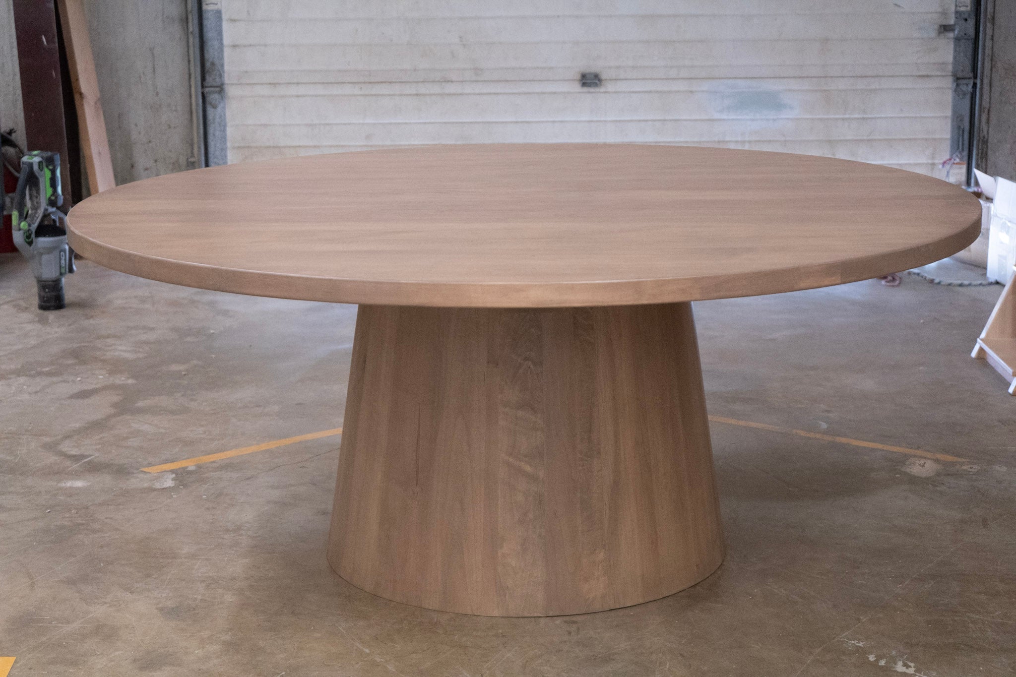 Wooden round table with a thick cone base in an indoor setting