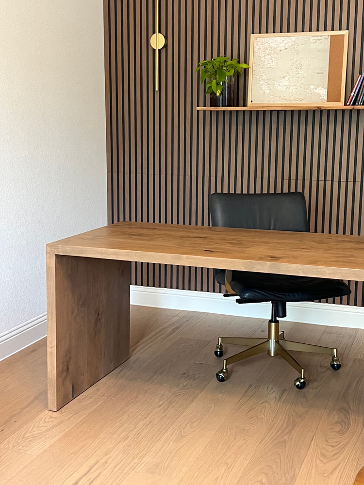 Wooden shelf with a black chair and fluted wall in the background