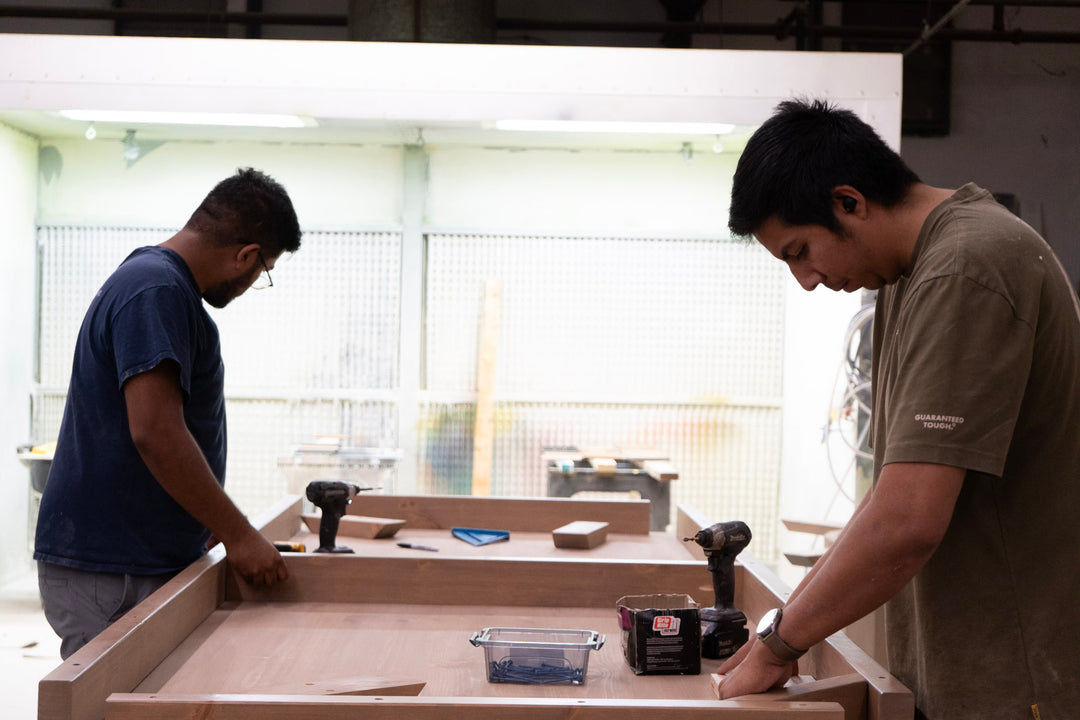 Two individuals working on a wooden project in a workshop.