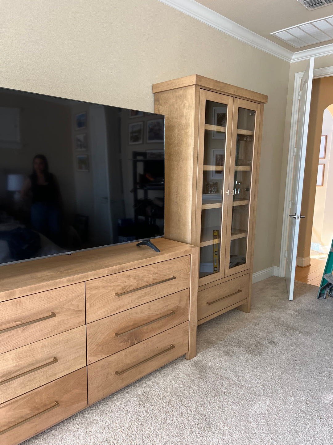 Wooden cabinet with glass doors and dresser in a bedroom.