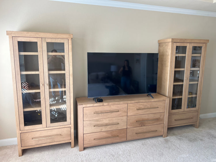 Wooden cabinet with glass doors and dresser in a bedroom.
