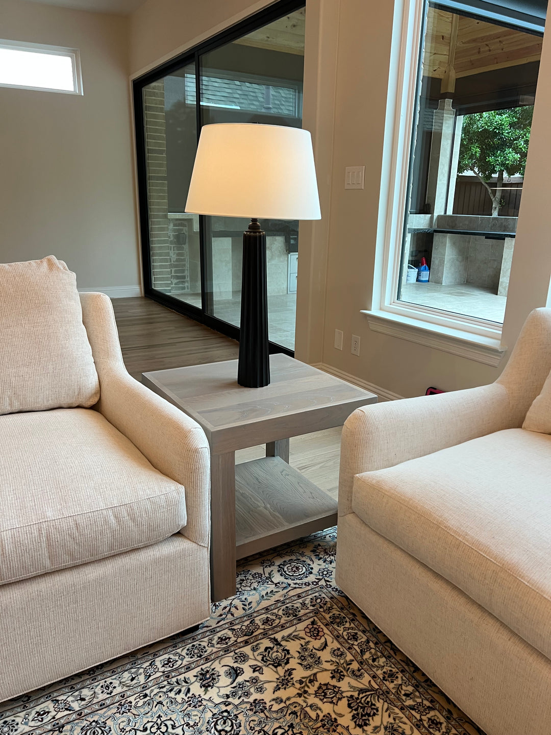 Beige sofa in a room with a skylight and patterned rug and a light gray side table white oak