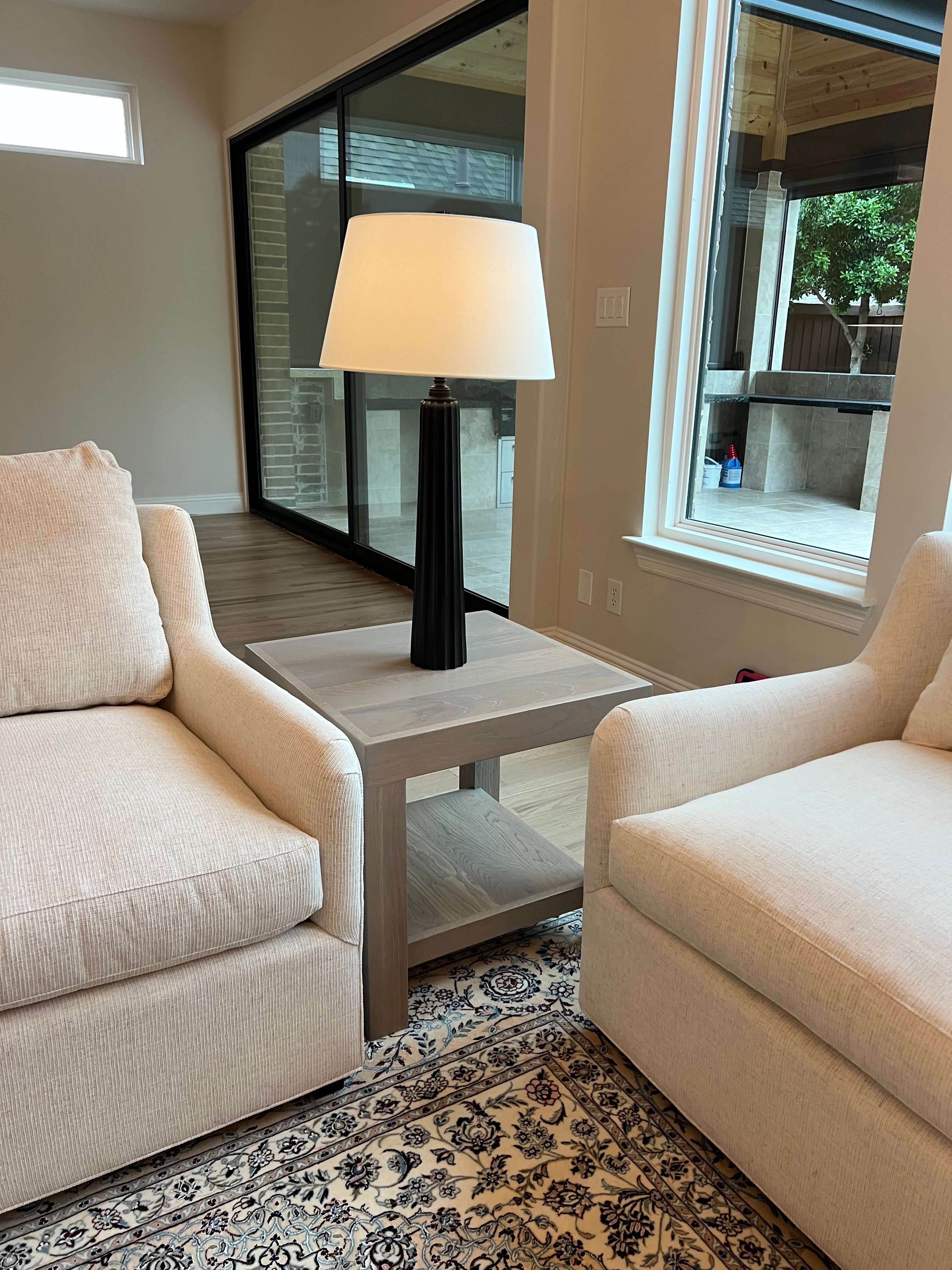 Beige sofa in a room with a skylight and patterned rug and a light gray side table white oak