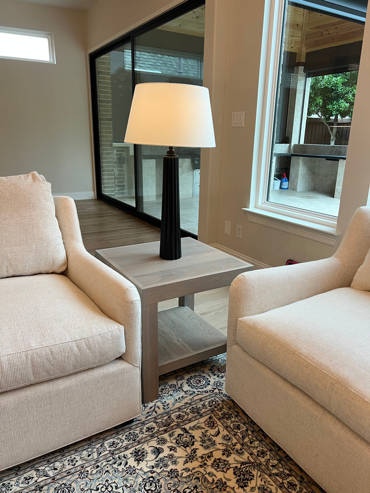 Beige sofa in a room with a skylight and patterned rug and a light gray side table white oak