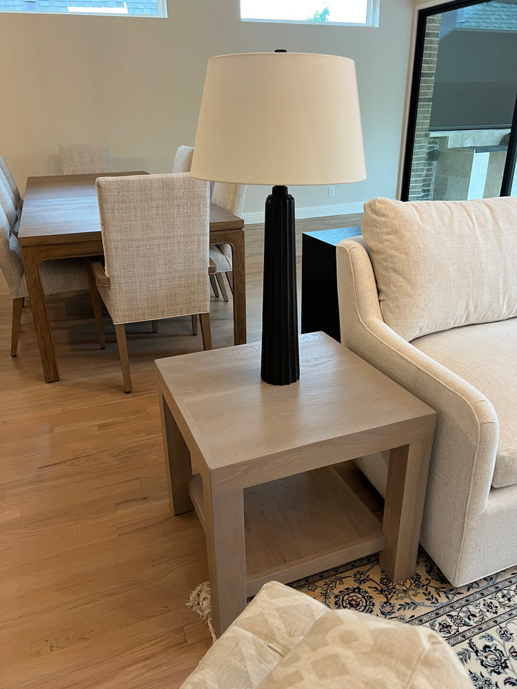 Beige sofa in a room with a skylight and patterned rug and a light gray side table white oak