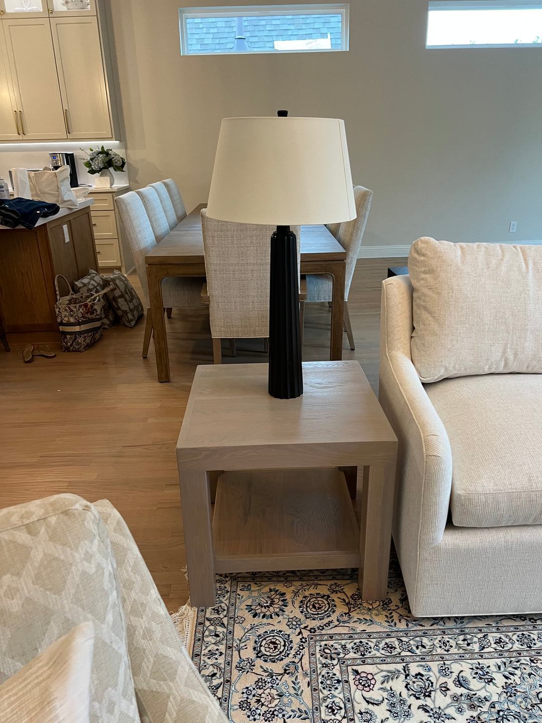 Beige sofa in a room with a skylight and patterned rug and a light gray side table white oak