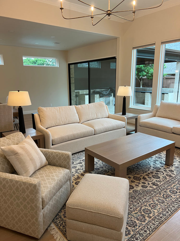 Beige sofa set in a modern living room with patterned rug and ceiling light fixture.